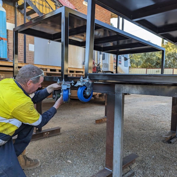Image showing Gup attaching wheels to custom made heavy duty workshop benches destined for a farm in Koorda.